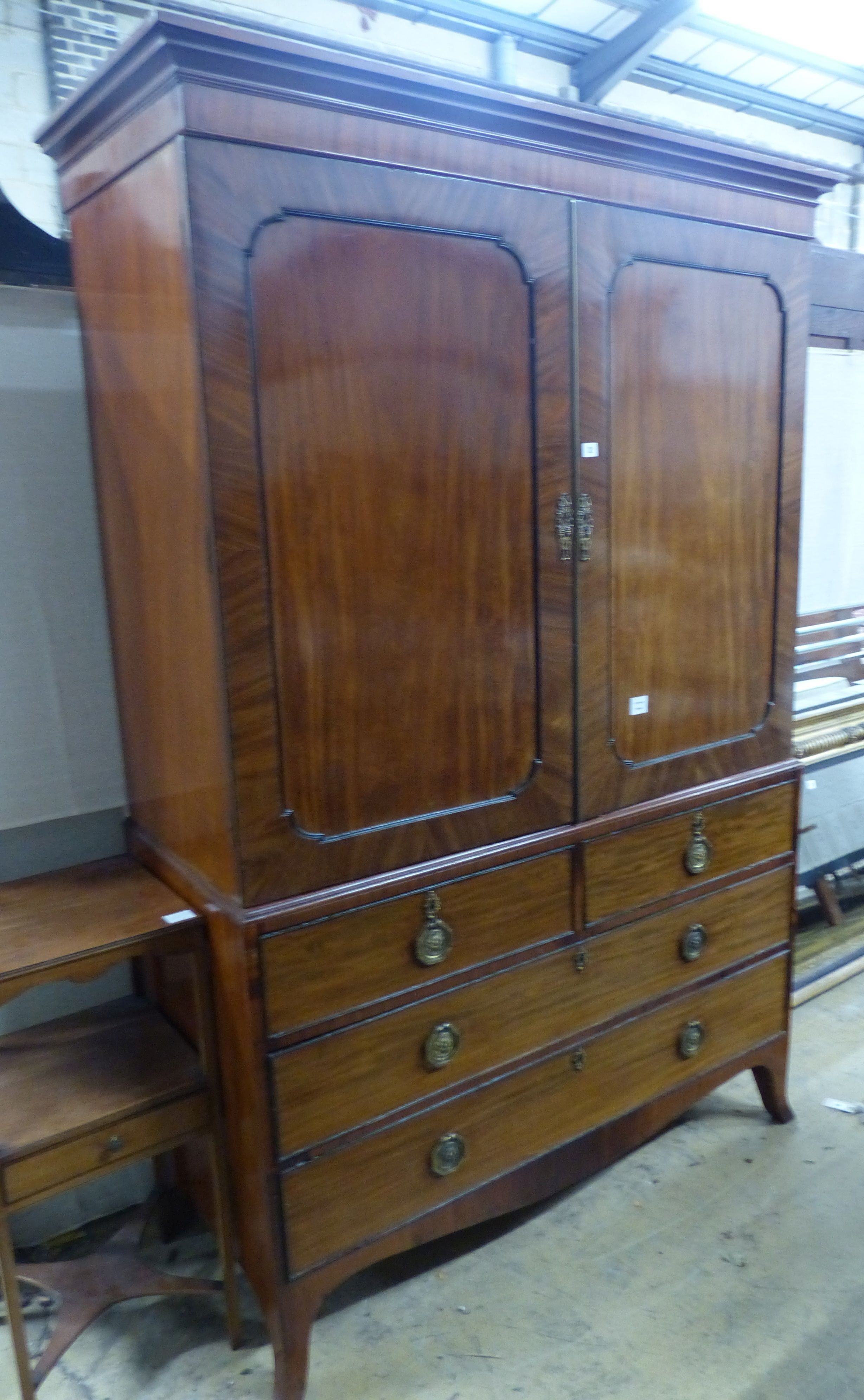 A George IV mahogany linen press, with a pair of hinged panelled doors over two short and two long drawers, on splay feet W.132 D.58 H.202 cms